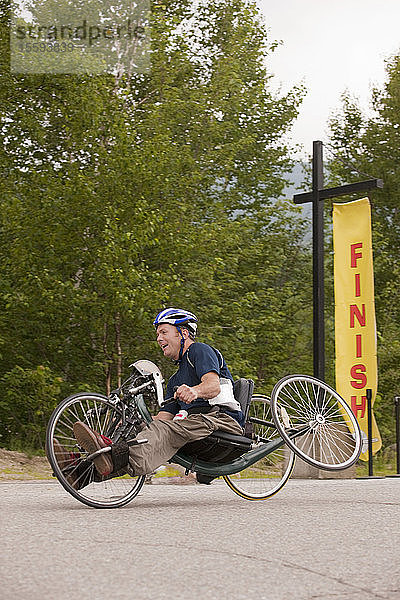 Mann mit Querschnittslähmung auf der Ziellinie eines Handbike-Rennens