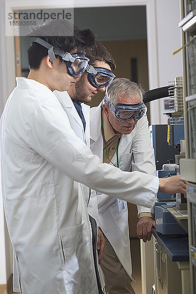 Professor arbeitet mit Studenten der Ingenieurwissenschaften an einem Instrument zur thermomechanischen Analyse in einem Labor