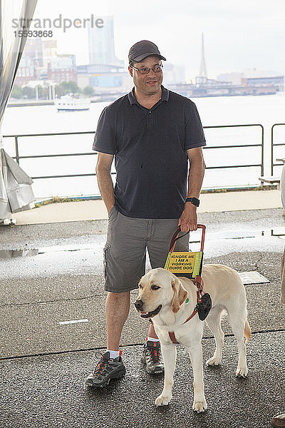 Mann mit Sehbehinderung und sein Diensthund