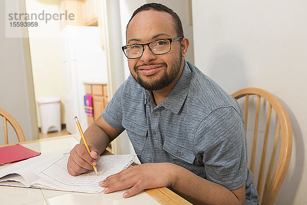 Glücklicher afroamerikanischer Mann mit Down-Syndrom erledigt Papierkram zu Hause