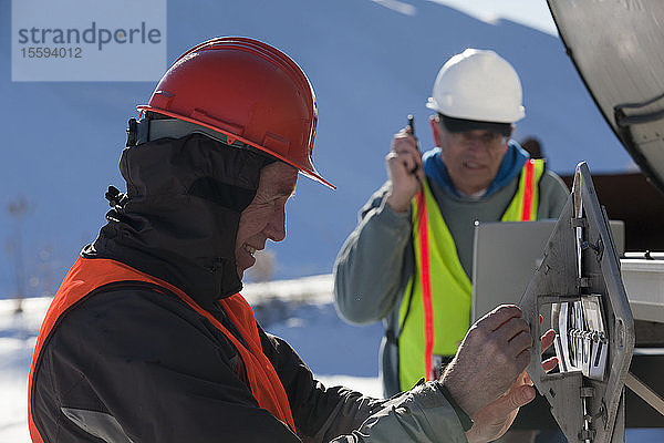 Ingenieure ändern das Sicherheitszeichen am Tankwagen und protokollieren die Daten auf dem Laptop