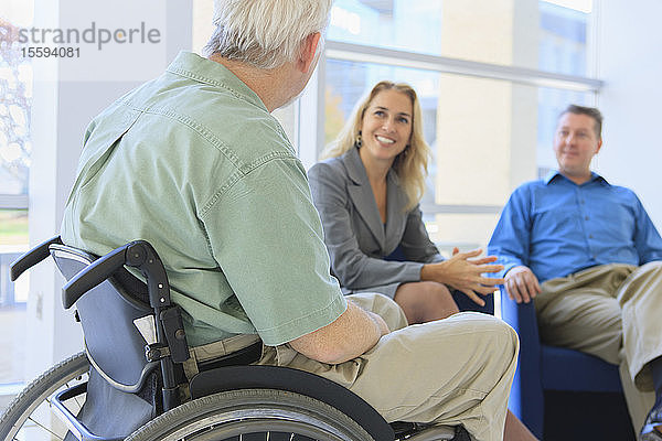 Mann mit Muskeldystrophie im Rollstuhl im Gespräch mit Freunden