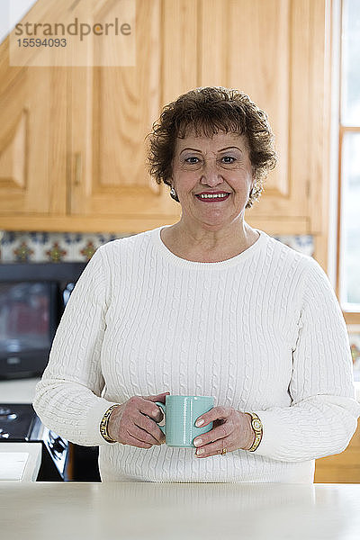 Porträt einer fröhlichen Frau  die eine Kaffeetasse hält.