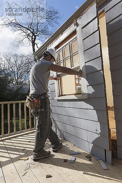 Hispanischer Schreiner beim Entfernen der neu geschnittenen Tür zum Deck eines Hauses