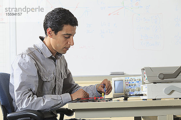 Ingenieurstudent beim Einsetzen eines Bauteils in ein Prototyping-Breadboard für ein Experiment im Elektroniklabor