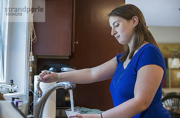 Junge Frau mit zerebraler Lähmung nimmt zu Hause ein Glas Wasser