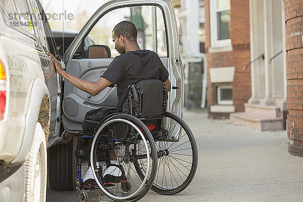 Mann im Rollstuhl  der an Spinaler Meningitis erkrankt war  betritt sein zugängliches Fahrzeug