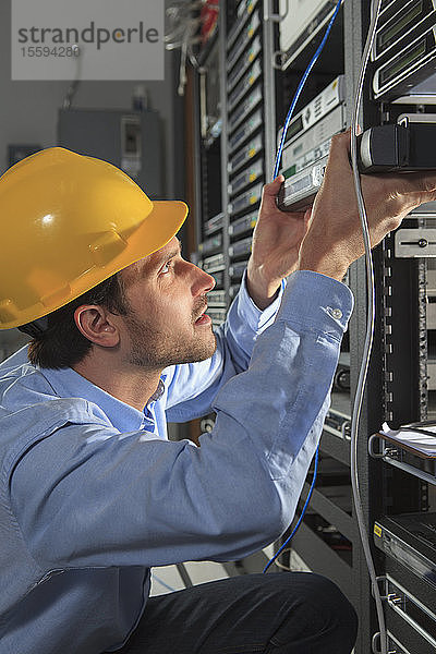 Netzwerktechniker bei der Installation von Kabelgeräten in einem Rack