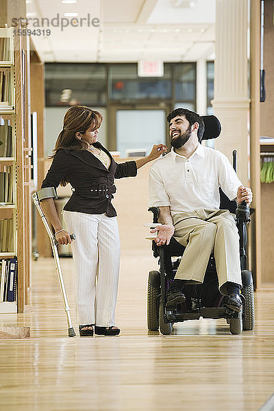 Blick auf einen Mann mit zerebraler Lähmung und eine Frau im Gespräch.