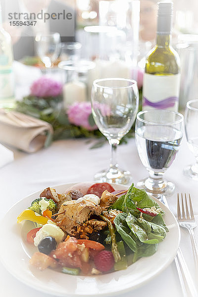 Formeller Tisch bei einer Hochzeit mit Teller voller Essen und Weinflasche mit Weingläsern; British Columbia  Kanada