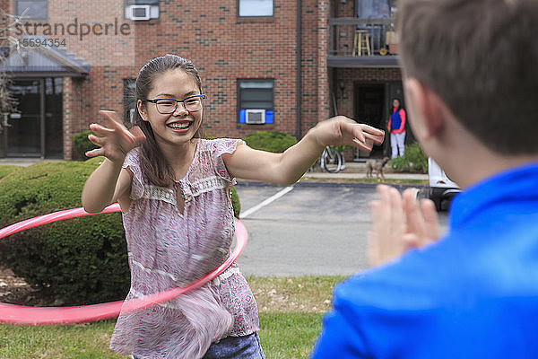 Ein lernbehindertes Mädchen spielt Hula-Hoop-Reifen mit ihrem Bruder