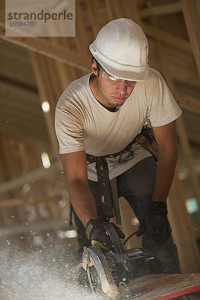 Zimmermann bei der Arbeit mit einer Kreissäge an einer Dachplatte in einem im Bau befindlichen Haus
