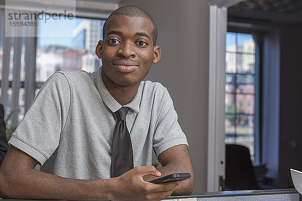 Porträt eines afroamerikanischen Mannes mit Autismus  der in einem Büro telefoniert