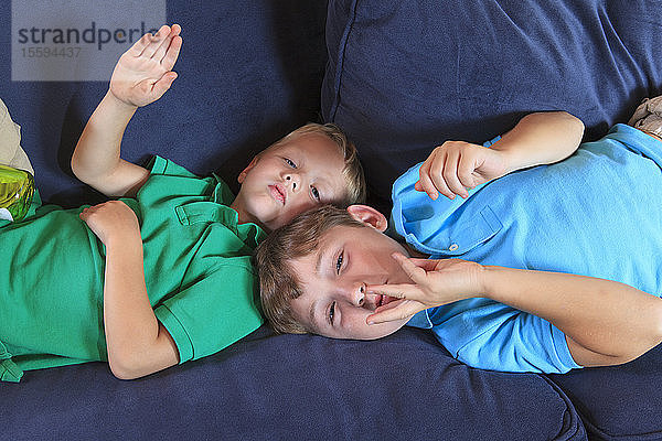 Hörgeschädigte Jungen  die auf ihrer Couch Wasserrutsche in amerikanischer Zeichensprache gebärden