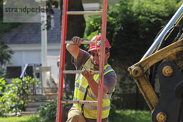 Bauarbeiter klettert über eine Leiter in einen Verbau
