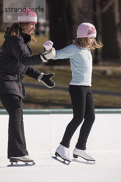 Trainerin hilft Mädchen beim Erlernen des Eiskunstlaufs
