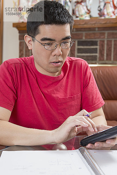 Asiatischer Mann mit Autismus arbeitet an seinem Mobiltelefon