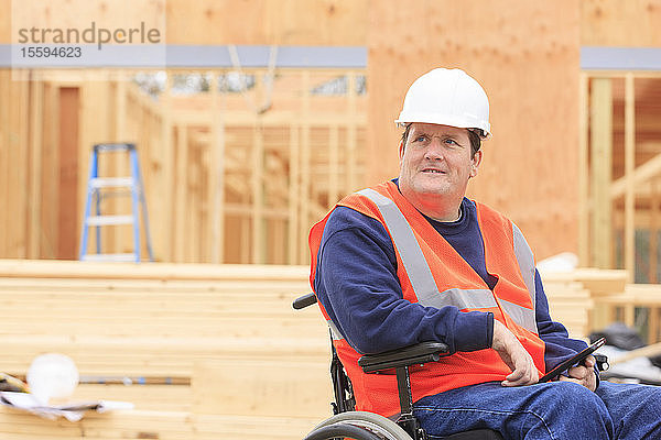 Bauingenieur mit Querschnittslähmung nutzt Tablet  um sich auf der Baustelle Notizen zu machen