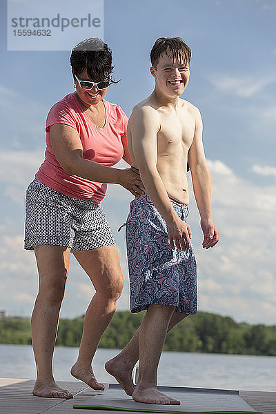 Junger Mann mit Down-Syndrom spielt mit seinem Freund auf einem Steg