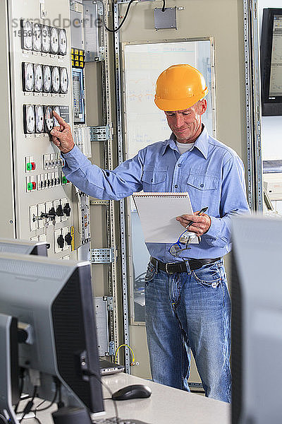 Elektroingenieur bei der Inspektion der Kraftwerkssteuerung im zentralen Betriebsraum des Kraftwerks