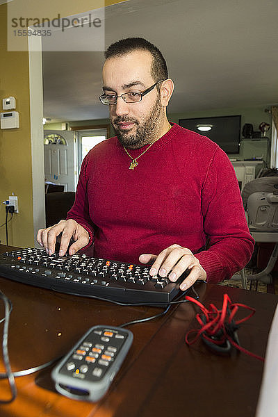 Mann mit Sehbehinderung an seiner Tastatur mit einem Bildschirmlesegerät