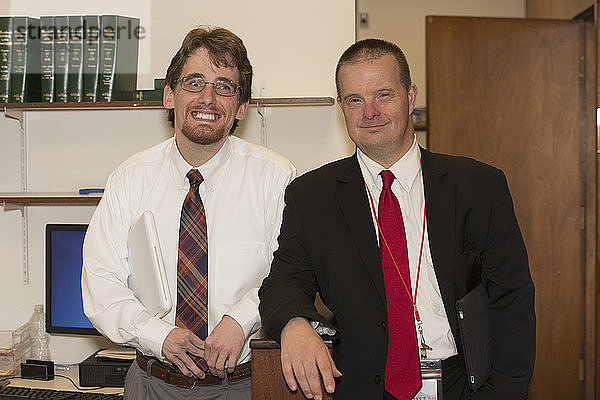 Porträt eines Mannes mit Down-Syndrom  der mit einem Mitarbeiter im Büro des State Capitol lächelt