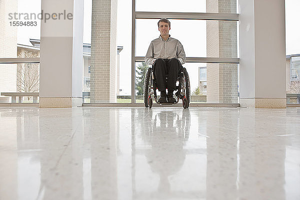 Geschäftsmann mit Querschnittslähmung im Rollstuhl in einem Bürogebäude