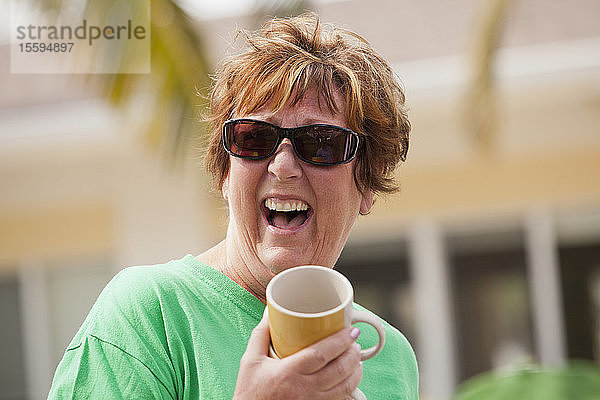 Ältere Frau hält eine Tasse und lacht