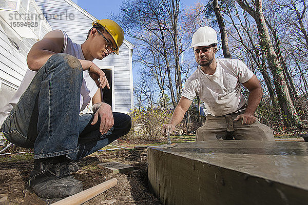 Spanische Zimmerleute glätten mit der Kelle den Beton für das Treppenfundament