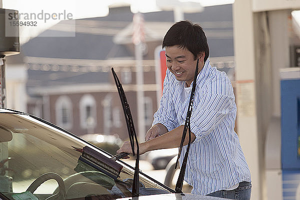 Chinesischer Mann wäscht die Windschutzscheibe seines Autos