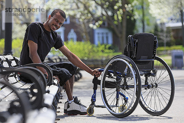 Mann mit Spinaler Meningitis sitzt auf einer Parkbank neben seinem Rollstuhl