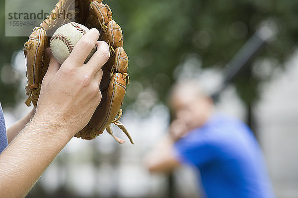 Nahaufnahme der Hand einer Person  die einen Baseballhandschuh trägt und einen Ball hält