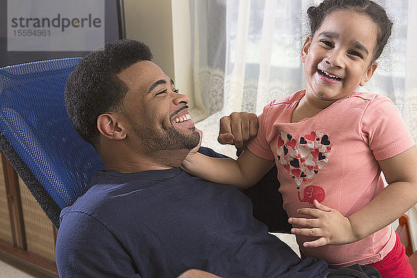 Afroamerikanischer Mann mit zerebraler Lähmung hat Spaß mit seiner Tochter zu Hause