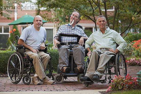 Drei Männer in Rollstühlen sitzend