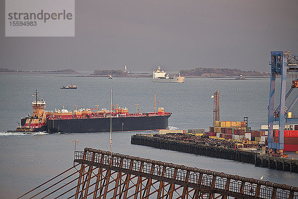 Containerschiff mit Kränen in einem Hafen mit Nixes Mate und Boston Lighthouse im Hintergrund  Boston Harbor  Boston  Massachusetts  USA