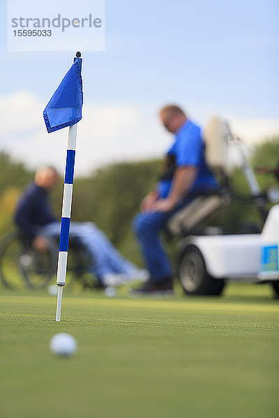 Zwei Männer mit Rückenmarksverletzungen warten am Golf-Putting-Green