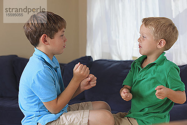 Jungen mit einer Hörbehinderung  die auf ihrer Couch in amerikanischer Gebärdensprache gewinnen gebärden