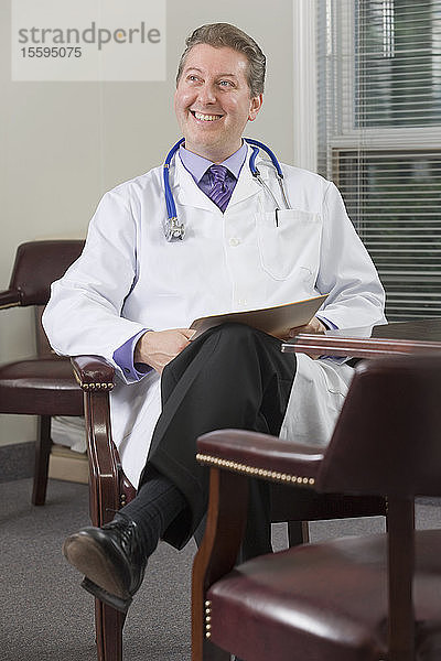 Arzt sitzt in seinem Büro und lächelt