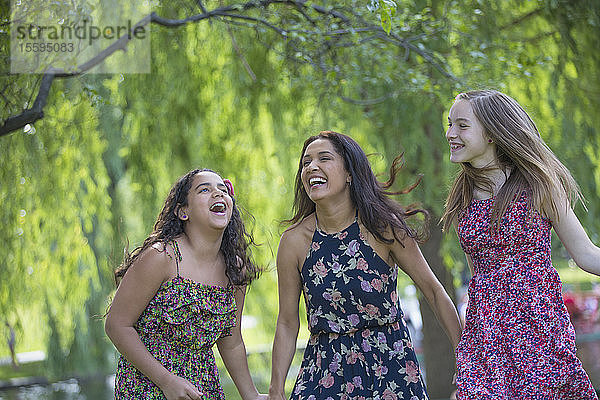 Glückliche hispanische Mutter und zwei Töchter im Teenageralter haben Spaß im Park