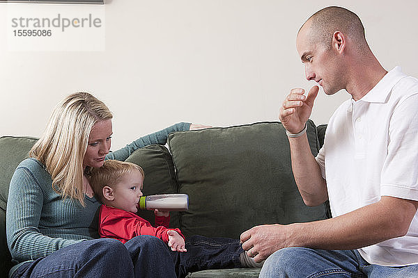 Mann gebärdet das Wort Drink in amerikanischer Zeichensprache  während sein Sohn Milch trinkt