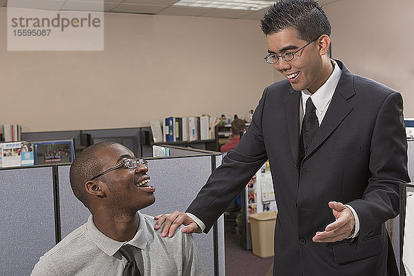 Zwei Männer mit Autismus reden und lächeln in einem Büro
