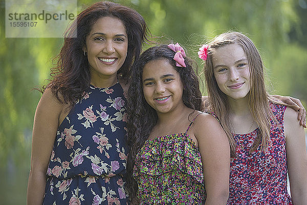 Porträt einer glücklichen hispanischen Mutter und zweier Teenager-Töchter mit Zahnspange im Park