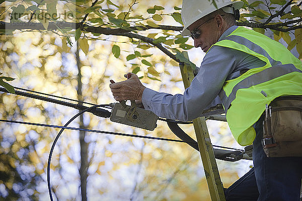 Ingenieur bei der Installation von Geräten an einem Strommast