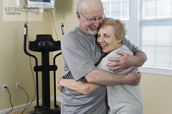 Älteres Paar  das sich nach dem Training an einem Fitnessgerät umarmt