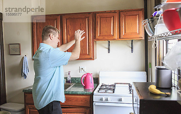 Mann mit Sehbehinderung arbeitet in der Küche seines Hauses