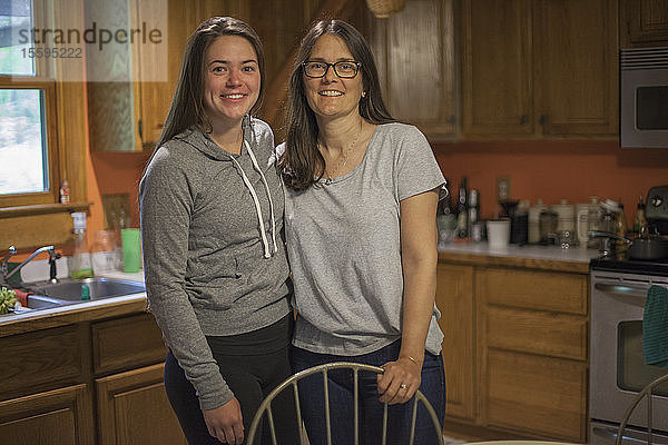 Frau mit Multipler Sklerose steht mit ihrer Tochter in der Küche
