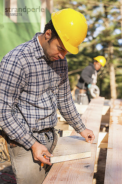 Zimmermann bei der Vorbereitung eines Schrägschnitts für einen Dachsparren eines Hauses
