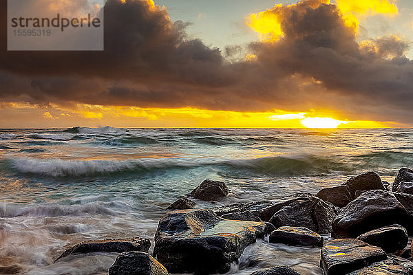 Sonnenaufgang über Strand und Meer mit Flut  die über Sand und Felsen spült; Kauai  Hawaii  Vereinigte Staaten von Amerika