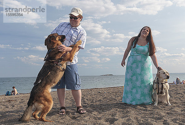 Ein blindes Paar vergnügt sich am Strand mit seinen Diensthunden