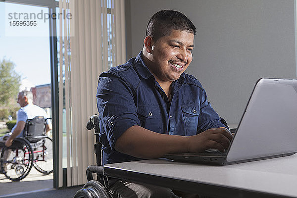 Hispanischer Mann im Rollstuhl mit Rückenmarksverletzung bei der Arbeit